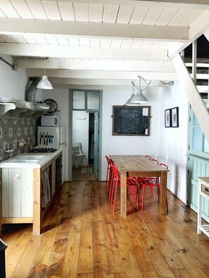 A kitchen with a wooden table and red chairs, a white sink, and a microwave. - Charming Rural Lodging in the Sierra de las Nieves · Casa Algarrobo (Tolox)