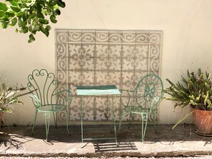 A small outdoor seating area with a metal table and chairs, a decorative wall, and potted plants. - Charming Rural Lodging in the Sierra de las Nieves · Casa Algarrobo (Tolox)