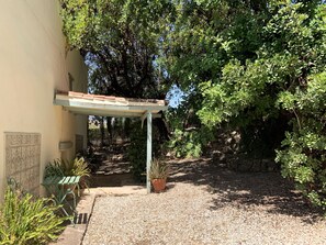 A covered outdoor seating area with a pergola, a stone wall, and a gravel path. - Charming Rural Lodging in the Sierra de las Nieves · Casa Algarrobo (Tolox)