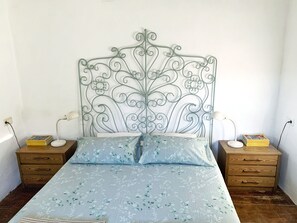 A bed with a metal headboard, two bedside tables with lamps, and a floral-patterned bedspread. - Charming Rural Lodging in the Sierra de las Nieves · Casa Algarrobo (Tolox)