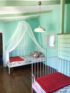 A room with a bed under a canopy, a small table, and a cabinet.