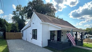 A single-story house with a gravel driveway, a wooden fence, and an American flag. - Welcome to “The Hideaway”..a cozy chalet in the heart of the Bourbon Capital (Bardstown)