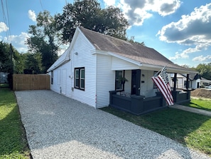 Een gelijkvloers huis met een grindpad, een houten hek en een Amerikaanse vlag.