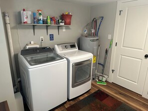 Un área de lavandería con dos lavadoras, un estante con productos de limpieza y una puerta con letrero de 'no entrar'.