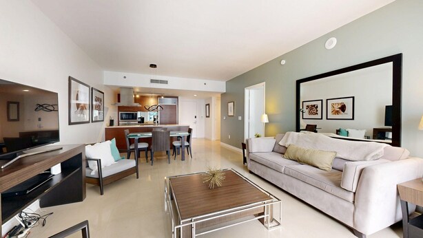 A modern living room with a sofa, coffee table, and a dining area with chairs and a table. - ICON Brickell High-Floor Condo, City Views, Pool & Spa (Miami)