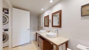Uma casa de banho com duas pias, uma banheira, um chuveiro e uma máquina de lavar roupa.