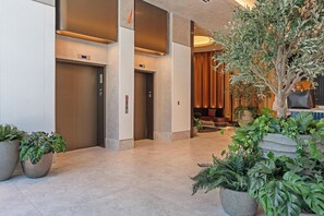 A modern lobby with elevators, a seating area, and potted plants. - Deluxe E11EVEN Studio Suite with Elite Amenities (Miami)