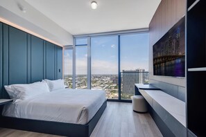 A modern bedroom with a large bed, a view of the city, and a mounted TV. - Deluxe E11EVEN Studio Suite with Elite Amenities (Miami)