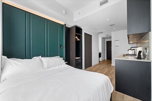 A modern hotel room with a large bed, a walk-in closet, a kitchenette, and a bathroom visible in the background. - Elite E11EVEN Condo with Rooftop Pool & Resort Gym (Miami)