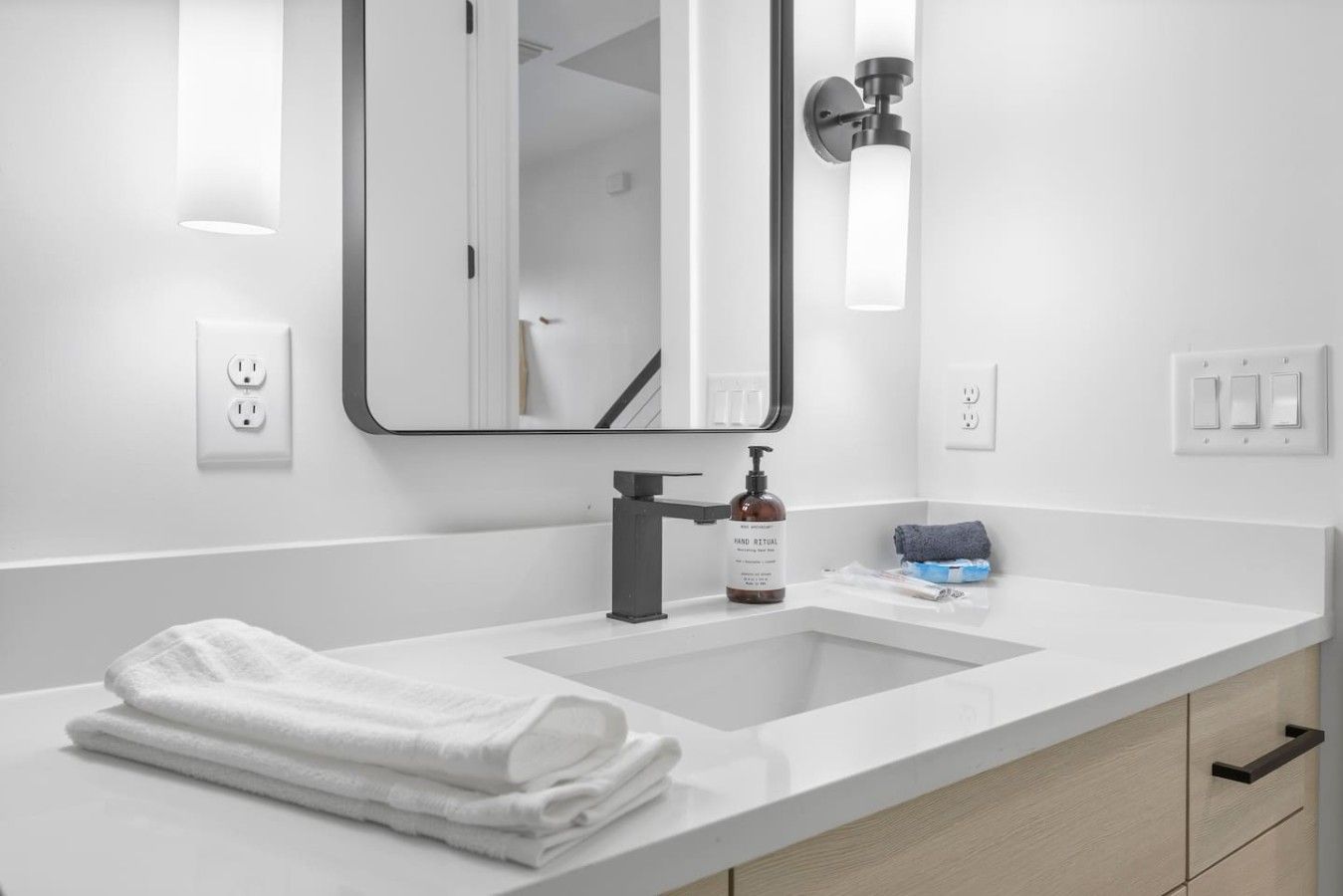 Un baño moderno con un lavamanos blanco, un espejo y una toalla.