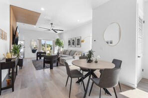 Ein modernes Wohnzimmer mit Essbereich, Deckenventilator und großem Fenster.