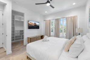 Ein Schlafzimmer mit einem großen Bett, einem Deckenventilator, einem Heizkörper, einem Kleiderschrank und einem Fenster mit Vorhängen.