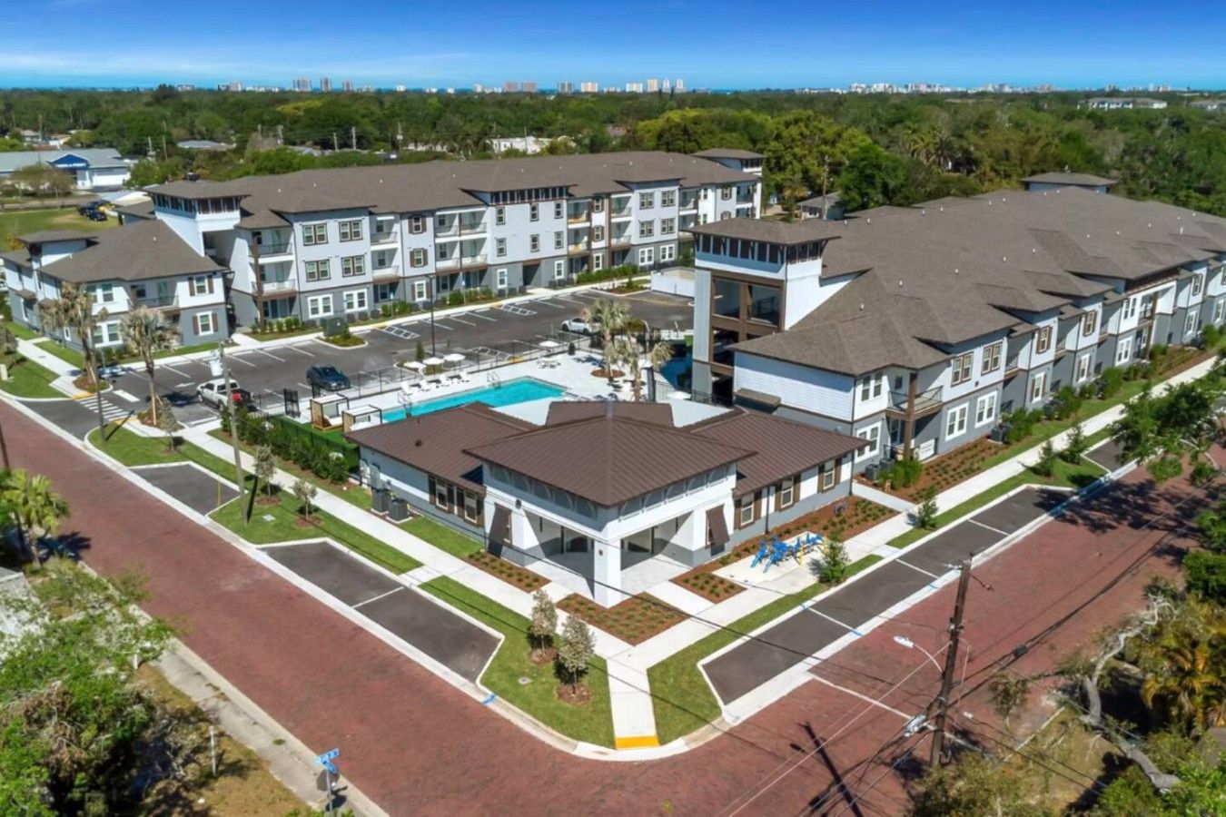A residential complex with multiple two-story buildings, a central swimming pool, and a parking area.