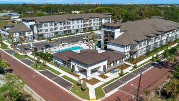 A residential complex with multiple two-story buildings, a central swimming pool, and a parking area.