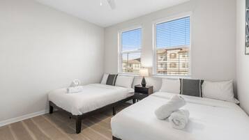 A hotel room with two beds, a ceiling fan, and a window with blinds.