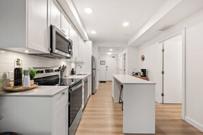 Eine moderne Küche mit Edelstahlgeräten, weißen Schränken und Holzboden.
