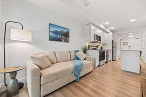 A modern living room with a sofa, a lamp, and a painting on the wall. - 2 Bed | Cgy Tower View | AC | Underground Parking (Calgary)