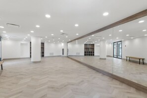 Ein geräumiger Raum mit einem großen Spiegel, Holzböden und eingelassenen Deckenleuchten.