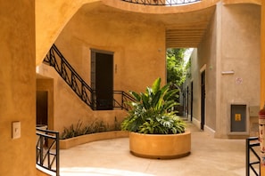 A circular courtyard with a central planter, a staircase, and a door marked with the number 201. - Hotel Casa Nuuma (Merida)