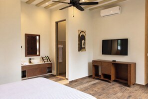 A bedroom with a bed, a wooden dresser, a TV, and a ceiling fan. - Hotel Casa Nuuma (Merida)