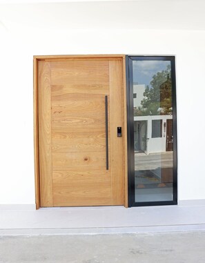 Een houten deur met een zwart handvat en een ruit.