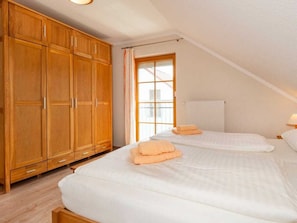 A bedroom with two beds, wooden wardrobe, and a window with curtains. - 8/t5 Holiday Home Park \"freesenbruch\" (Zingst)