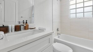 A modern bathroom with a white sink, a toilet, and a bathtub. - South Tampa Stay | Free Parking (Tampa)