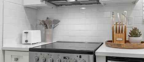 A kitchen with a built-in microwave, a toaster, a stove, and a set of knives on the counter.