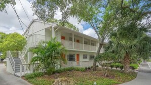A two-story building with a balcony, surrounded by greenery and a paved walkway. - South Tampa Stay | Free Parking (Tampa)