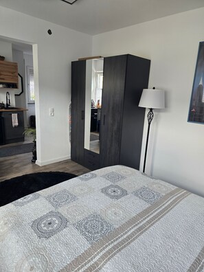 Een slaapkamer met een bed, een kast, een spiegel, een lamp en een schilderij aan de muur.