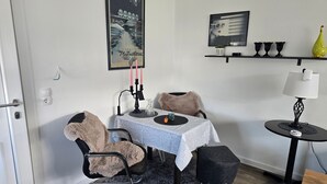 Un comedor con una mesa, sillas, una lámpara y una estantería con objetos decorativos.