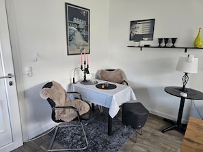 En matplats med ett bord, stolar, en lampa och en hylla med dekorativa föremål.