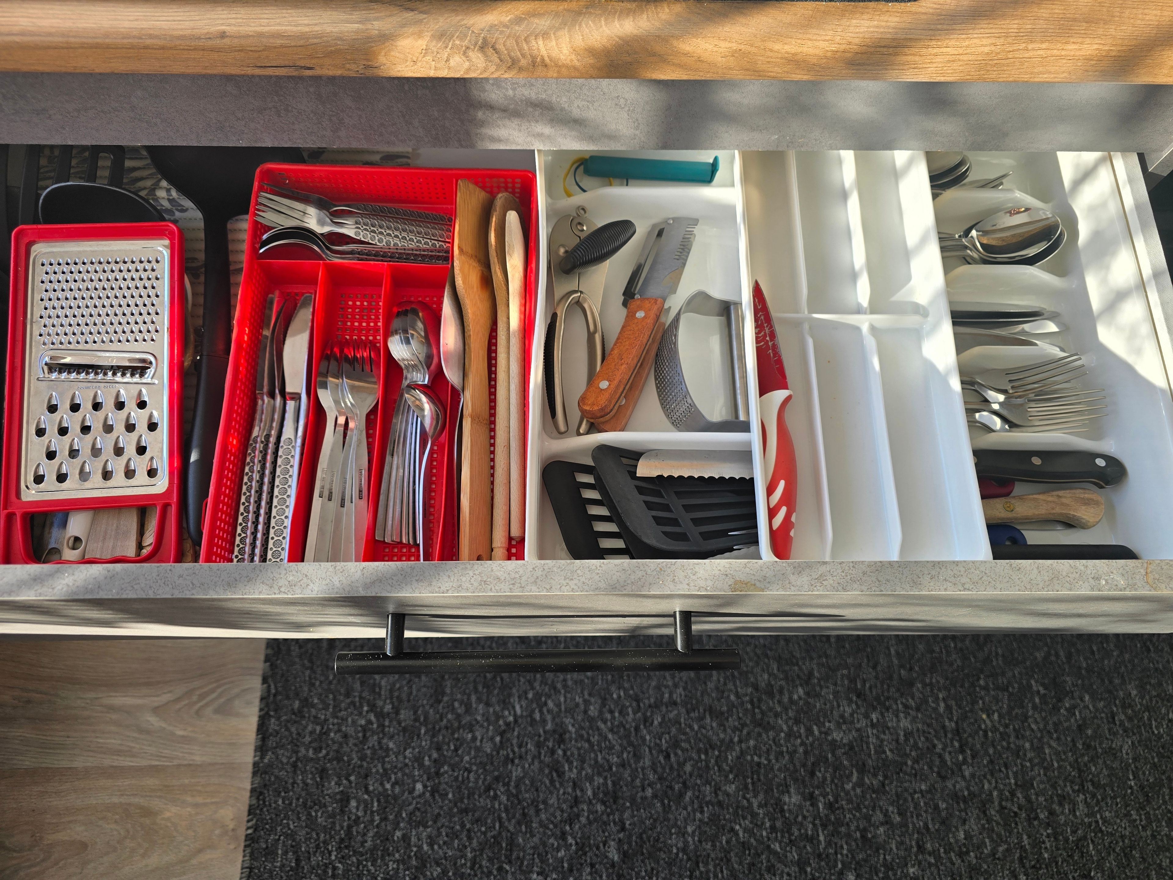 A drawer with various kitchen utensils and tools organized in compartments.