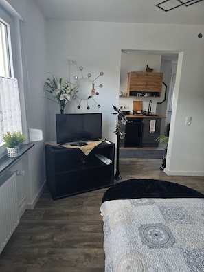 Ett modernt vardagsrum med en platt-TV, en svart möbel för underhållningssystemet, en dekorativ spegel och en svart matta.