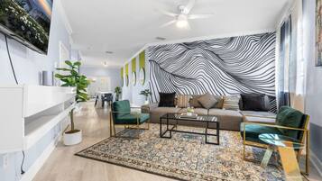 A modern living room with a sofa, two armchairs, a coffee table, and a patterned rug.