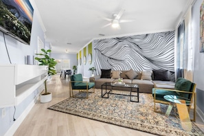 Una sala de estar moderna con un sofá, dos sillones, una mesa baja y una alfombra estampada.