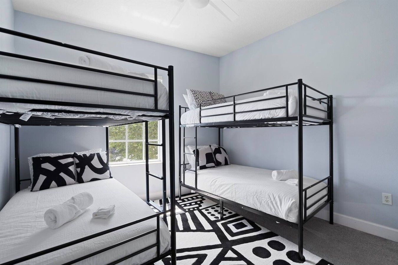 A room with bunk beds, a patterned rug, and a window.