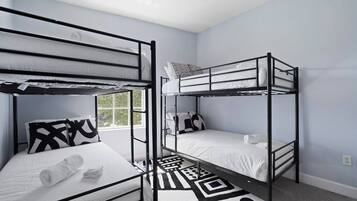 A room with bunk beds, a patterned rug, and a window.