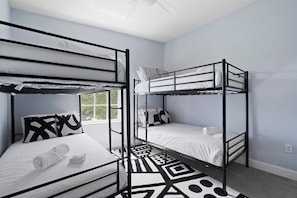 Una habitación con literas, un tapete estampado y un ventanal.