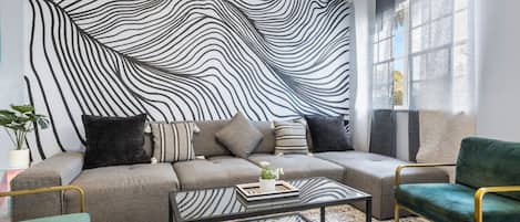 Una sala de estar moderna con un sofá, dos sillones, una mesita de centro y un tapete estampado.