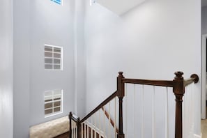 Una escalera con barandilla de madera y balaustres blancos que conduce a una plataforma con un banco acolchado.