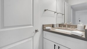 A bathroom with a double sink, a large mirror, and a towel rack. - Walk to Bayshore | Pool, Gym & Parking (Tampa)