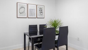 A dining area with a table and chairs, framed artwork on the wall, and a potted plant. - Walk to Bayshore | Pool, Gym & Parking (Tampa)