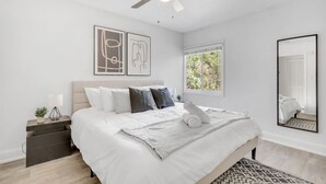 A bedroom with a bed, a ceiling fan, a window, and artwork on the wall. - Walk to Bayshore | Pool, Gym & Parking (Tampa)