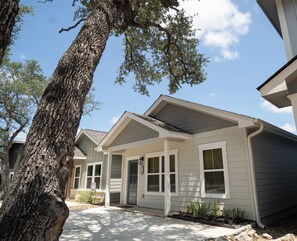 Une maison d’habitation avec un porche à l’avant, une allée et un arbre.