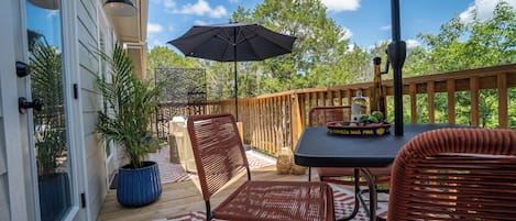 An outdoor patio with wicker furniture, a table, and a potted plant.
