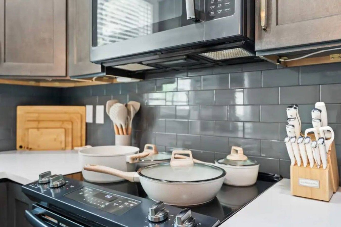 Una cocina moderna con estufa, ollas, sartenes y un juego de cuchillos.