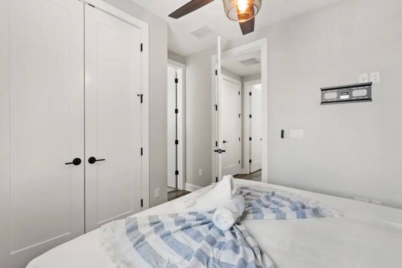 A hotel room with a bed, white walls, and a ceiling fan.