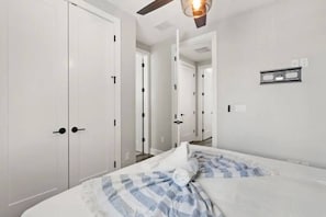 A hotel room with a bed, white walls, and a ceiling fan.