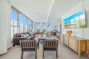 A spacious living area with a sofa, chairs, a dining table, and a kitchen with modern appliances. - The Reef 7C - Island Horizon (Noord)